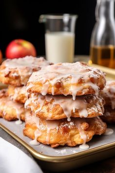 there are several donuts on the plate with icing and apples in the background