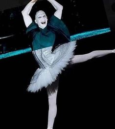 a ballerina in white and green posing for the camera with her arms stretched out