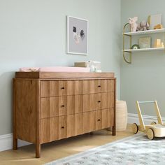 a baby's room with a wooden dresser and toy car in the foreground