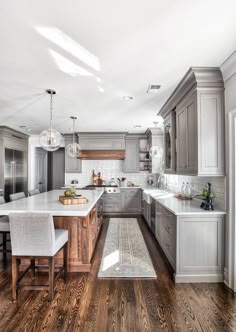 a large kitchen with wooden floors and gray cabinets