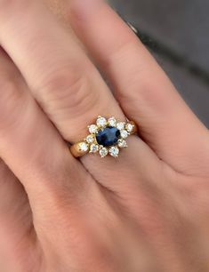 a woman's hand with a gold and blue diamond ring on top of it