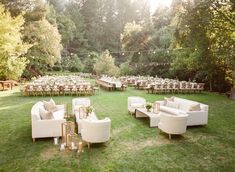 an outdoor seating area with white couches and tables set up for a wedding reception