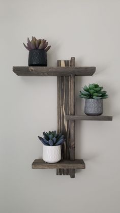 three wooden shelves with succulents and pots on them against a white wall