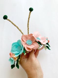 a hand holding a flower arrangement made out of felt and twine with green stems