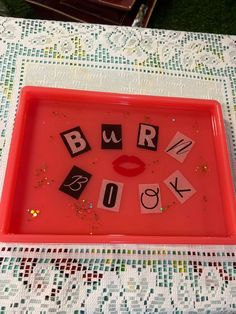 a red tray with letters spelling out the word's on it and a lipstick - shaped mouth