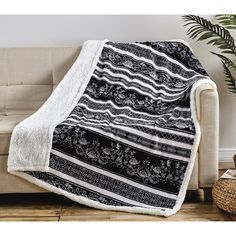 a black and white blanket sitting on top of a couch next to a potted plant