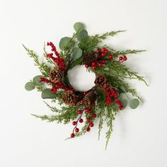 a wreath with pine cones, berries and greenery on white background for christmas decoration