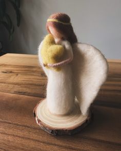 a needled angel figurine sitting on top of a piece of wood