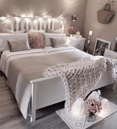 a bedroom with white furniture and lights on the headboard, bedding and pillows