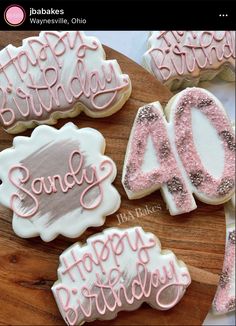 decorated cookies with the words happy birthday written in pink and white frosting on a wooden platter