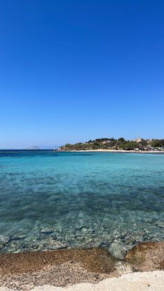 the clear blue water is in front of an island