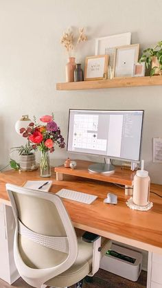 a desk with a computer and flowers on it