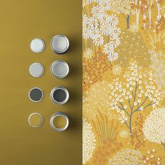 the wallpaper is yellow with white flowers on it and four tins are placed next to each other