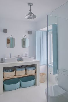 a bathroom with white walls and blue baskets on the shelf next to the sink area