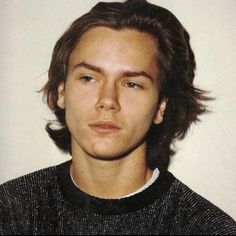 a young man with long hair wearing a sweater