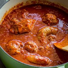 meatballs and tomato sauce in a green pot with a wooden spoon on the side