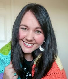 a woman with long black hair smiling and holding a cell phone up to her ear