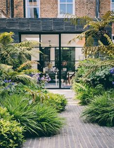 a person sitting at a table in the middle of a courtyard surrounded by greenery