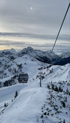 a ski lift going up the side of a snow covered mountain with mountains in the background