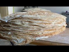 a large stack of food sitting on top of a wooden table next to a knife