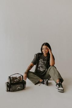 a woman sitting on the floor next to a bag and suitcase with her eyes closed