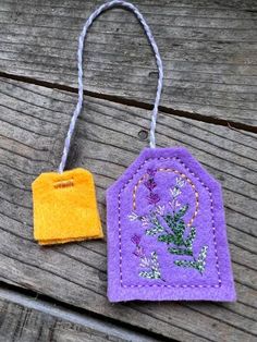 two felt tags with flowers on them sitting on a wooden surface