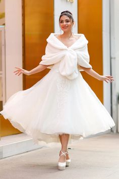 a woman in a white dress is walking down the street with her arms out and hands outstretched