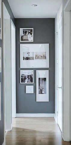 an empty hallway with pictures on the wall and wood flooring in front of it