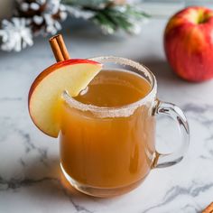 an apple cider is garnished with cinnamon and apples on a marble table