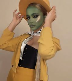 a woman with green face paint and a hat on her head wearing a yellow outfit