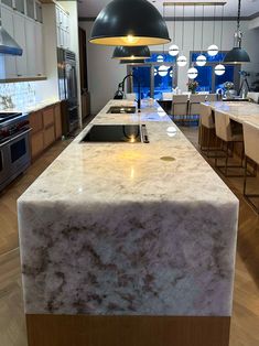 a large kitchen with marble counter tops and pendant lights