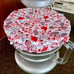 a close up of a kitchen mixer on a counter top with red and white designs