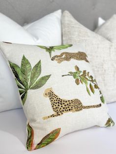 the pillows are decorated with leopards, leaves and plants on white bed linens