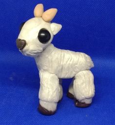 a small white toy with horns on it's head and legs, standing in front of a blue background