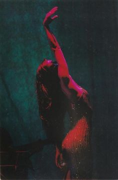 a woman is dancing on stage with her arms in the air