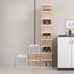 a tall white cabinet sitting next to a shoe rack filled with pairs of shoes on top of it