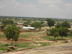 a rural area with houses and trees in the foreground, surrounded by dirt roads