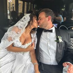 a bride and groom kissing on the back of a car in front of a crowd