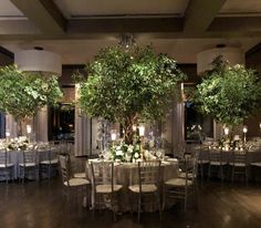 the tables are set up with white linens and silver tablecloths, surrounded by greenery