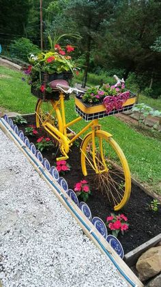 a yellow bicycle with flowers in the basket is parked next to some rocks and grass