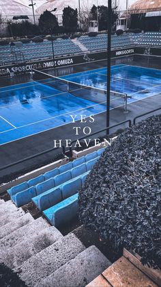 an empty tennis court with blue seats and the words yes to heaven written on it