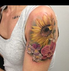 a woman with a sunflower and orchid tattoo on her left upper arm, which is covered in flowers