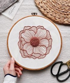 someone is working on an embroidery project with scissors and other crafting supplies around it