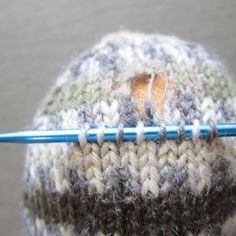 a knitted hat with a crochet stitch on it and a blue knitting needle