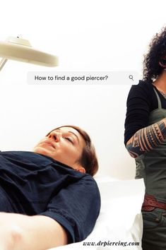 a man laying on top of a bed next to a woman with arm tattoos and an electric hair dryer