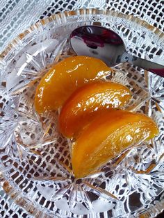 three pieces of fruit sitting on top of a glass plate next to a knife and spoon