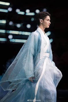 a woman is walking down the runway in a blue dress