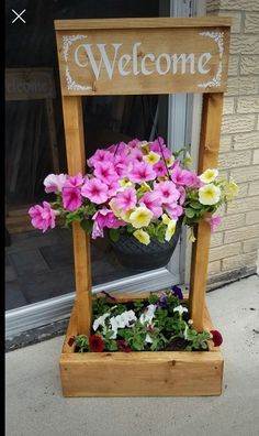 a wooden welcome sign with flowers in it