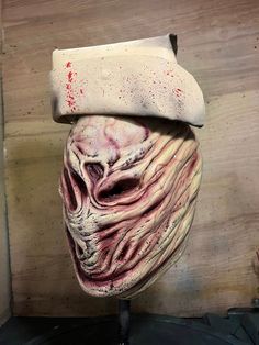 an odd looking mask with blood on it's face sitting on top of a table