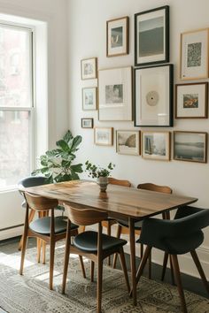 a dining room table with chairs and pictures on the wall above it, along with a potted plant